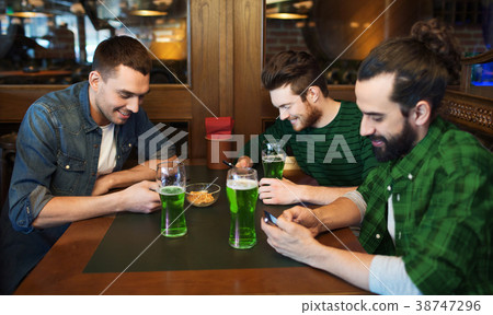 friends with smarphones and green beer at pub friends with smarphones and green beer at pub 38747296