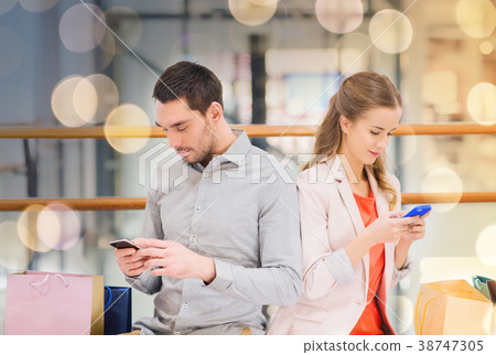 couple with smartphones and shopping bags in mall couple with smartphones and shopping bags in mall 38747305