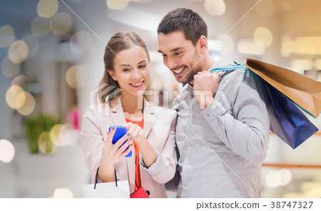 couple with smartphone and shopping bags in mall couple with smartphone and shopping bags in mall 38747327