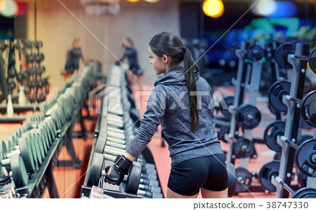 young woman choosing dumbbells in gym young woman choosing dumbbells in gym 38747330