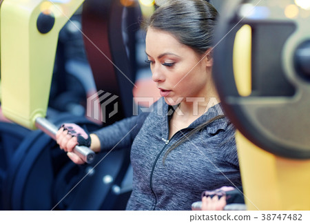 woman flexing muscles on chest press gym machine 38747482