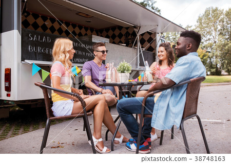 friends with drinks sitting at table at food truck 38748163