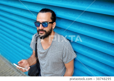 man in sunglasses with smartphone and bag at wall man in sunglasses with smartphone and bag at wall 38748295
