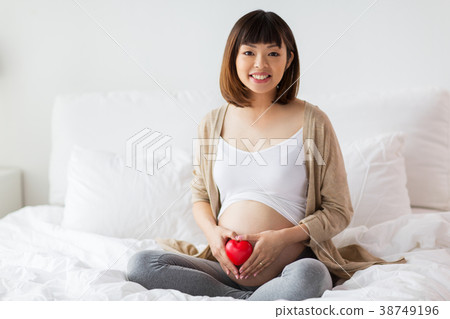 happy pregnant asian woman with red heart in bed happy pregnant asian woman with red heart in bed 38749196