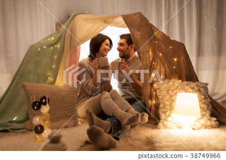 couple drinking coffee or tea in kids tent at home couple drinking coffee or tea in kids tent at home 38749966