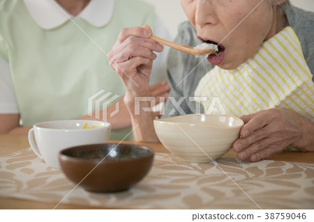 Senior woman eating carp and care worker 38759046