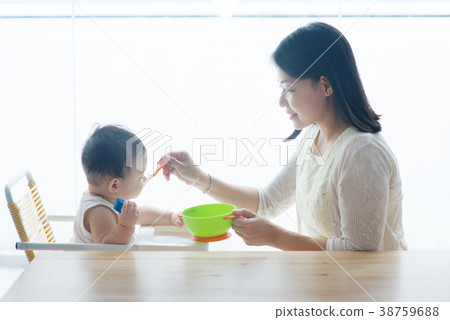 Mother feeding toddler. 38759688