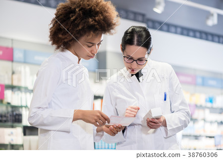 Two pharmacists comparing medicines regarding Two pharmacists comparing medicines regarding 38760306