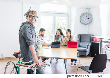 Cheerful young woman holding her commuter bike in 38760339