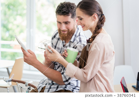 Two co-workers smiling while watching a video on 38760341