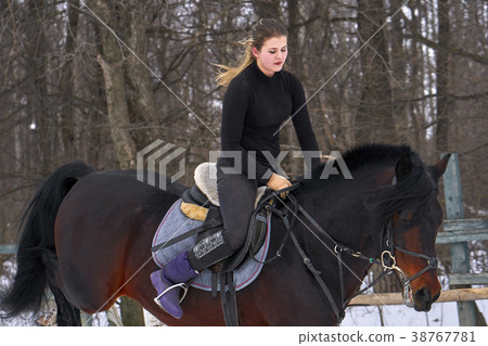 A girl on a horse jumps over the barrier.  38767781