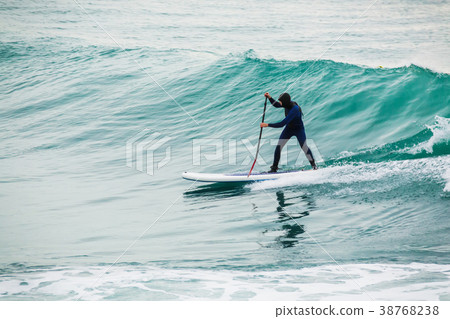 Surfer on stand up paddle board on blue wave Surfer on stand up paddle board on blue wave 38768238