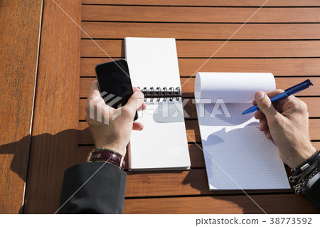 Man in suit at the table and writing in notebook. Man in suit at the table and writing in notebook. 38773592