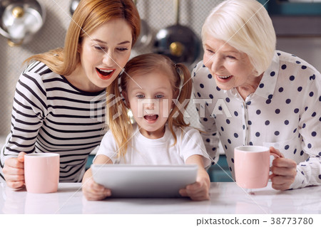 Cute girl watching cartoon on tablet with mother Cute girl watching cartoon on tablet with mother 38773780