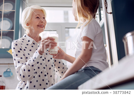 Little girl accepting glass of milk from Little girl accepting glass of milk from 38773842