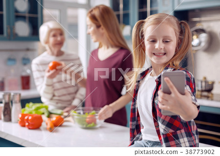 Smiling girl taking selfie while mother and 38773902
