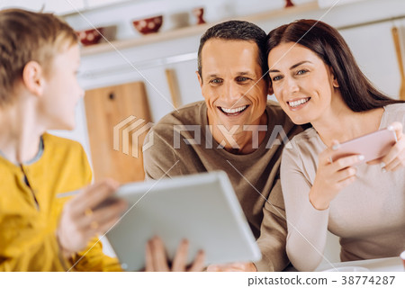 Happy boy showing something on tablet to his 38774287