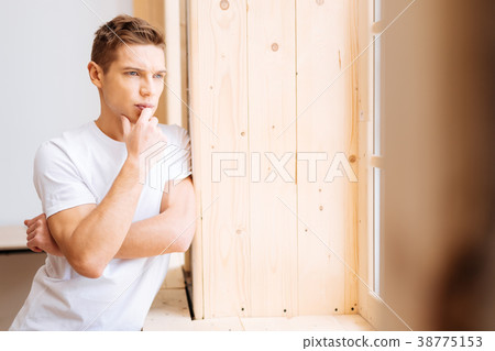 Troubled young man looking out the window Troubled young man looking out the window 38775153