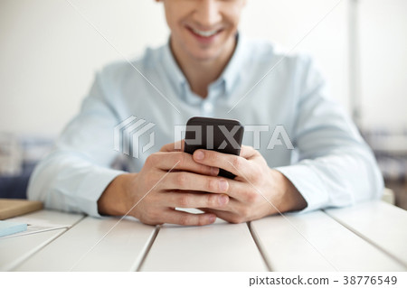 Smiling man typing on a modern phone 38776549