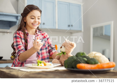 Happy girl feeding her toy with healthy food 38777515