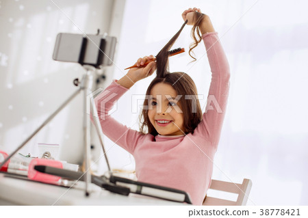 Happy girl recording herself while brushing hair Happy girl recording herself while brushing hair 38778421