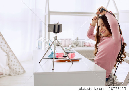 Cute beauty vlogger curling her hair while 38778425