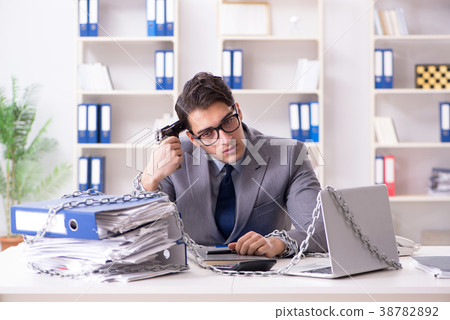 Busy employee chained to his office desk Busy employee chained to his office desk 38782892