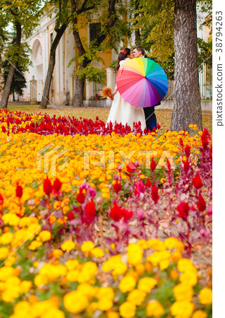 Newlyweds in the park with big umbrella Newlyweds in the park with big umbrella 38794263