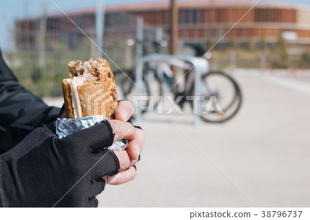 young cyclist man eating a sandwich 38796737