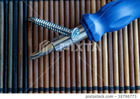 Screws and screwdriver on wooden background 38798773
