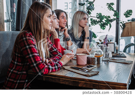Side view of a Four smiling friends sitting by the 38800428
