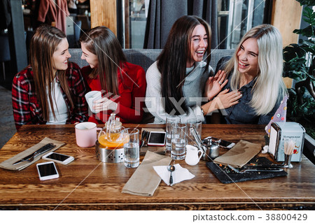 four friends in the cafe look at the camera and 38800429