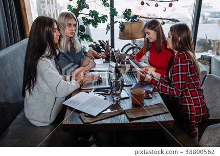 young women having conversation in cafe and using young women having conversation in cafe and using 38800562