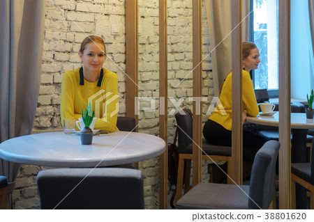 Pretty girl in cafe behind the table near mirror 38801620