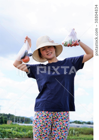 Agricultural girl holding harvested vegetables in both hands Agricultural girl holding harvested vegetables in both hands 38804834
