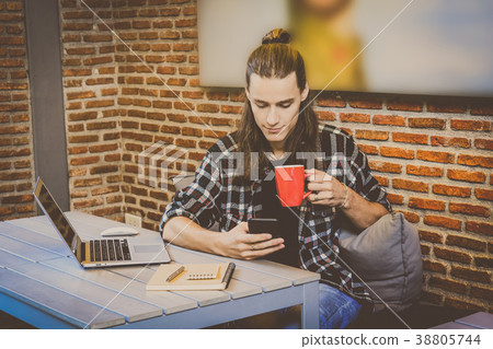 Hipster young man freelancer using smart phone mobile and laptop for working in the Loft cafe workplace. Creative Startup and entrepreneur business concept Hipster young man freelancer using smart phone mobile and laptop for working in the Loft cafe workplace. Creative Startup and entrepreneur business concept 38805744