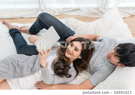 Top view of Lover using the digital tablet at modern home sleeping on the bed, Couple Lover and lifestyle concept Top view of Lover using the digital tablet at modern home sleeping on the bed, Couple Lover and lifestyle concept 38805821