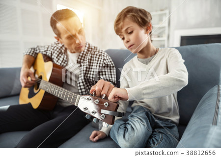 Happy father teaching his son to play the guitar 38812656