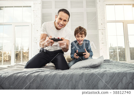 Cheerful dad and son playing games Cheerful dad and son playing games 38812740