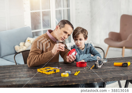 Serious daddy showing instruments to his son 38813016