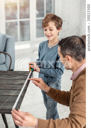 Exuberant daddy helping his son measure the table 38813300