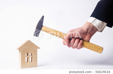 A man is striking with a hammer a wooden house A man is striking with a hammer a wooden house 38824616