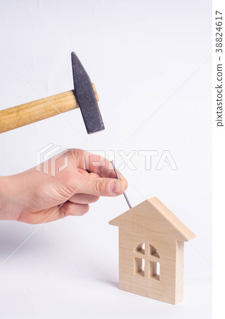 Man hammers a nail in a wooden house Man hammers a nail in a wooden house 38824617