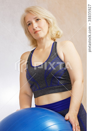 A confident contented woman at the age of 48 in a sports suit with a fitball 38835927