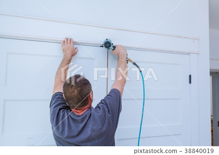 Carpenter brad using nail gun to moldings on doors 38840019