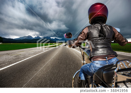 Biker girl on a motorcycle hurtling down the road 38841956