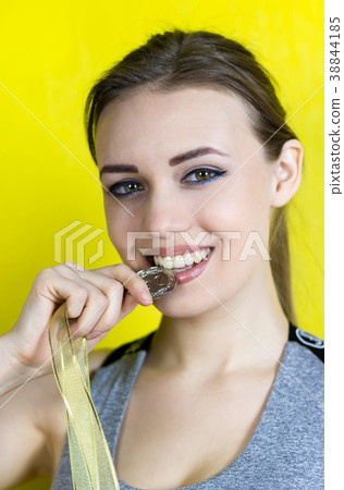 The champion of sports competitions bites his gold medal. 38844185