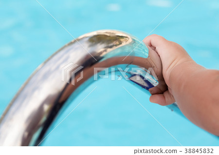 Child's hand holding a handrail in swimming pool Child's hand holding a handrail in swimming pool 38845832