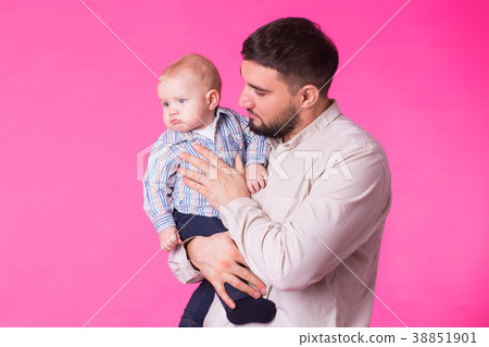 Happy father holding baby son in hands over pink Happy father holding baby son in hands over pink 38851901