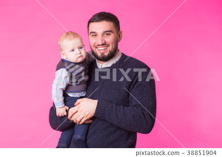 Happy father holding baby son in hands over pink Happy father holding baby son in hands over pink 38851904